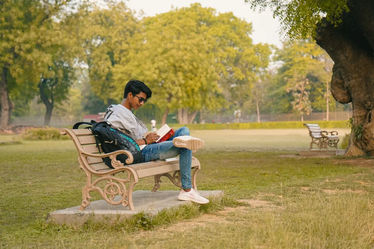 person reading leadership book park bench