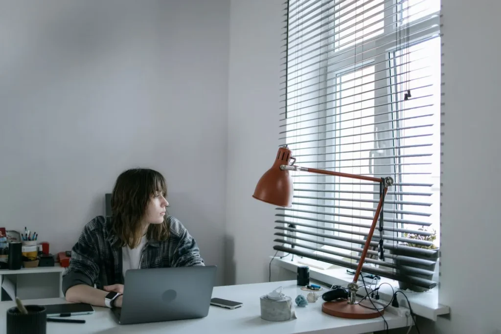 woman looking thoughtful at desk in office self-doubt