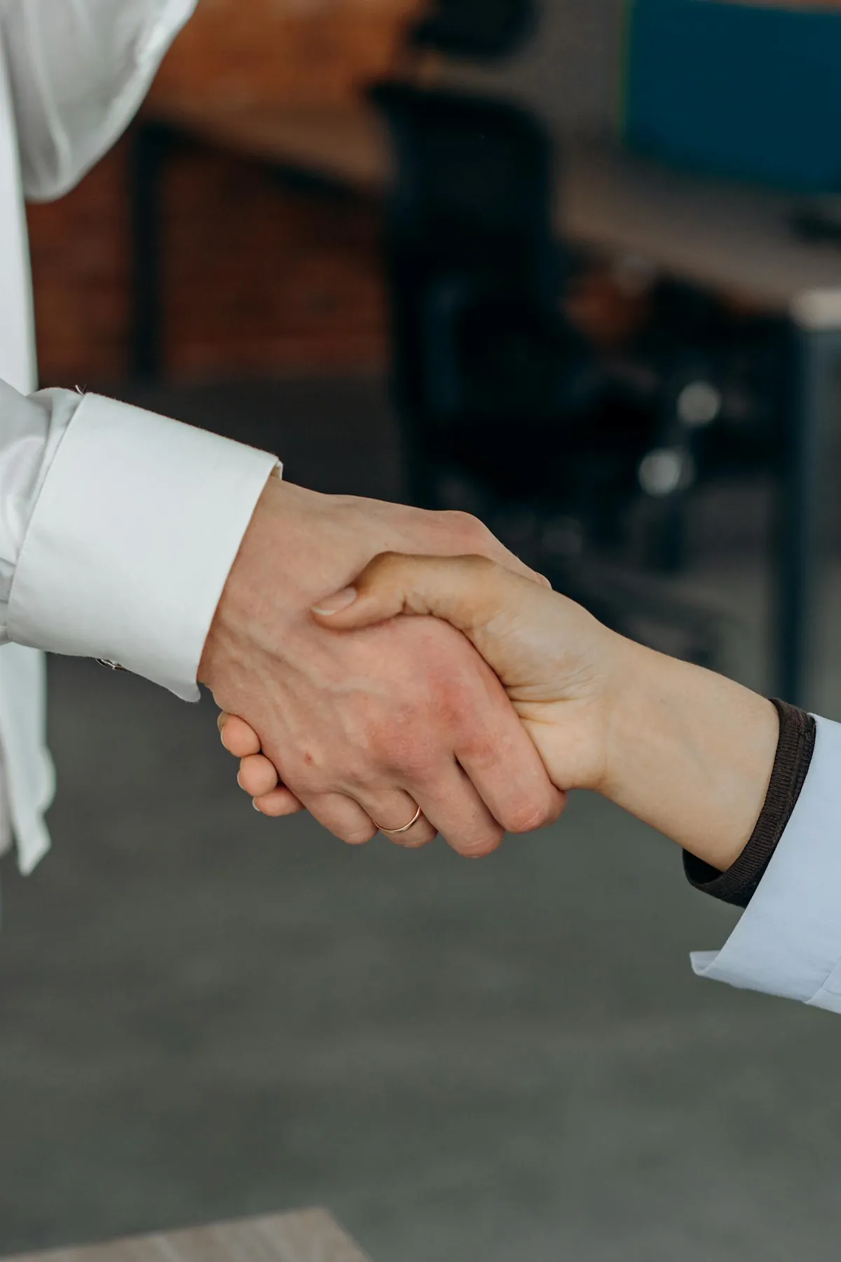 two people shaking hands across office desk job offer